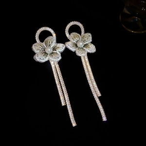 Détail macro de boucles d'oreilles fleurs en perles avec pompons scintillants