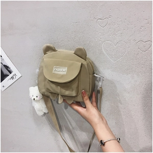 Detail of khaki nylon bag with bear ears, fashion label, and a plush bear charm