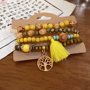 Detailed view of bohemian sandalwood bead bracelet with life tree charm and yellow silk tassel