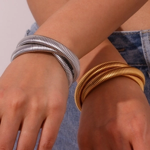 Detail of layered gold and silver snake chain bracelet on denim wrist background