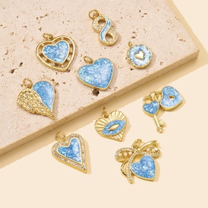 Gold-plated opal charms set with heart, butterfly and evil eye pendants on beige stone