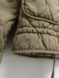 Detailed macro shot of the olive green quilted jacket showing diamond stitching and seams
