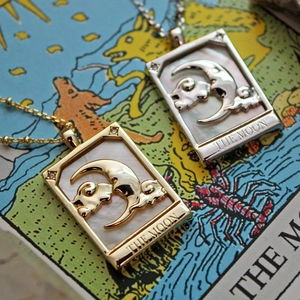 Detail view of gold and silver tarot moon pendants featuring mother of pearl inlay