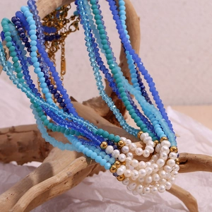 Multilayer beaded necklace featuring blue crystals and white pearls on driftwood display