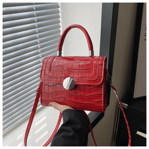 Macro detail of red crocodile texture handbag with glossy finish and silver buckle