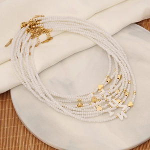 Shell letter necklaces with crystal beads and gold pendants on a marble tray