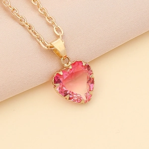 Macro detail of a pink heart-shaped crystal pendant with a gold-plated claw setting