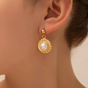 Detail of vintage gold flower earring with large white pearl on model's ear
