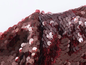 Dettaglio macro di paillettes rosso scuro e finiture di un abito da festa di lusso
