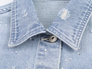 Vue détaillée du col de veste en jean bleu clair avec strass et boutons métalliques