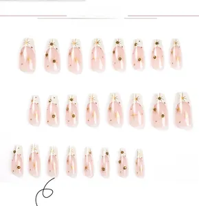 Detailed view of French tip press-on nails with gold star patterns and rhinestones