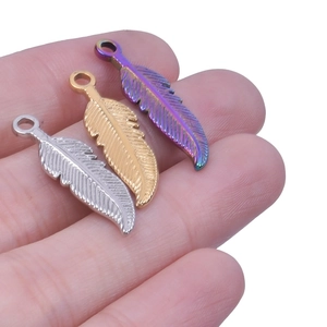 Macro view of three stainless steel feather pendants in silver gold and rainbow colors