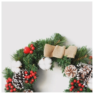 Close-up of Christmas wreath with natural pine cones, red berries and jute bow decoration