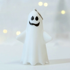 Close-up of a cute white ghost keychain with a smiling face and metal ring for Halloween