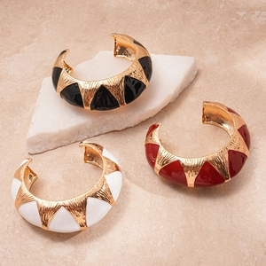 Three wide open gold metal bangles with black red white enamel geometric textures on stones