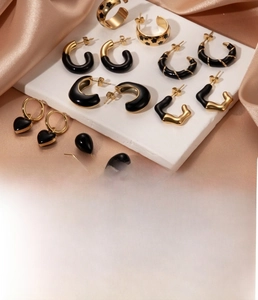 Macro shot of gold-plated stainless steel earrings with black heart and C-shaped details