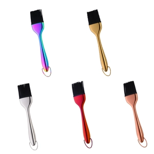 Cinque pennelli da cucina in silicone con manici in acciaio inox colorato su sfondo bianco
