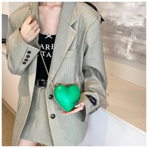 Detail of a green heart-shaped crossbody bag with a delicate gold metal chain strap