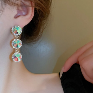 Détail de boucles d'oreilles dorées avec cristaux irisés et diamants étincelants