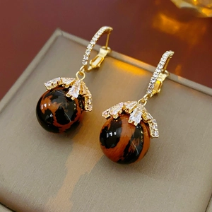 Macro shot of leopard print ball earrings with gold metal and sparkling zircon details