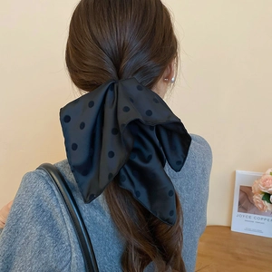 Dettaglio di un grande fermaglio per capelli in raso nero a pois per uno stile elegante