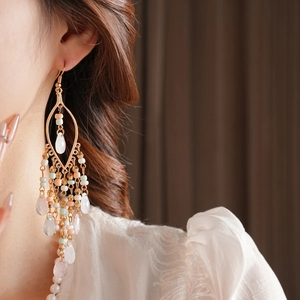 Bohemian acrylic bead tassel drop earrings with gold hooks worn by a female model