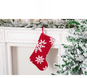 Close-up of red plush Christmas stocking with white snowflake patterns on mantel