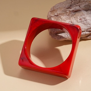 Macro shot of dark red marble acrylic square bangle on a natural stone base