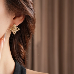 Close-up of elegant gold hollow flower stud earrings with shimmering zircon stones