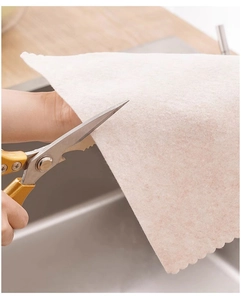 Detail showing a person cutting a beige loofah dishcloth to custom size with scissors