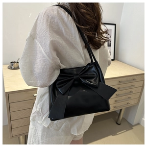 Detail shot of a black PU leather shoulder bag featuring a large decorative bow on the front