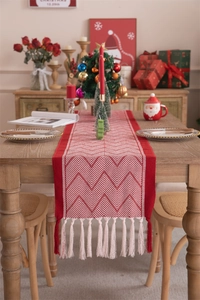 Close-up of red and white herringbone table runner with elegant white tassels on wood