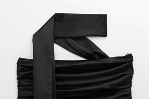Close-up of black satin fabric with pleated details and elegant shoulder strap design