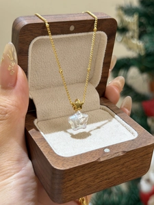 Gros plan d'un collier en perle étoilée sur chaîne dorée dans un écrin en bois chic