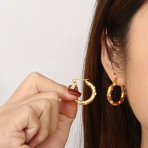 Detail shot of gold-plated U-shaped hoop earrings featuring inlaid sparkling zircon stones