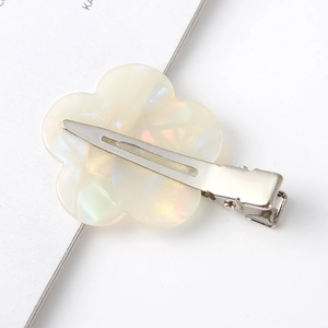 Macro view of the metal duckbill clip back and iridescent cream flower hair accessory