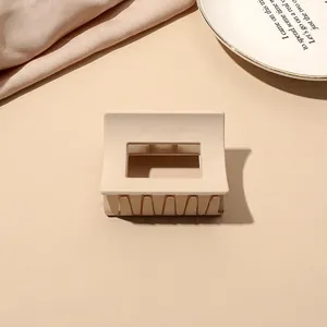 Close-up of minimalist matte cream rectangle hair claw clip on elegant prop plate
