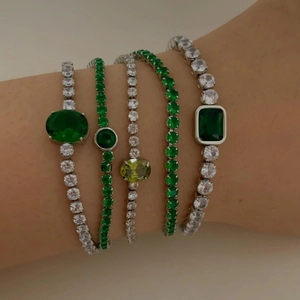 Close-up of stacked emerald and lime green zircon chain bracelets on a female model wrist