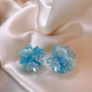 Gros plan de boucles d'oreilles fleurs bleues sur tissu en soie beige avec drapé élégant