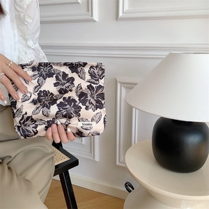 Detailed view of floral cotton makeup bag with zipper closure and brand label