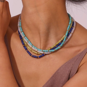 Macro shot of layered necklaces with blue and green beads and gold metal spacers