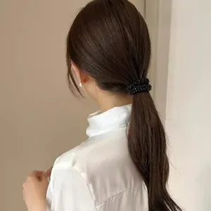 Close-up of black beaded elastic hair tie worn on a ponytail with glossy bead finish