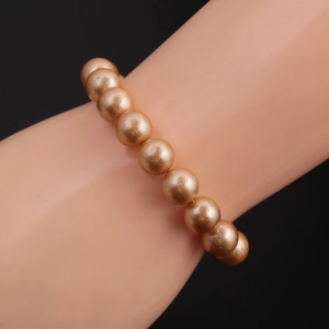 Macro view of champagne gold pearl bracelet with satin texture on a display arm