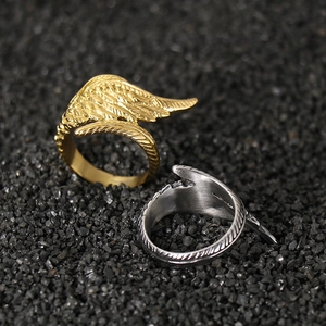 Vintage stainless steel angel wing rings in gold and silver on black sand background