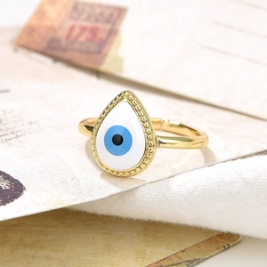 Close-up of golden evil eye adjustable ring with blue enamel and metallic bead accents