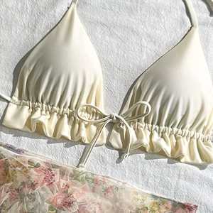 Detail of cream halter bikini top with ruffle edges and pink floral mesh fabric cover