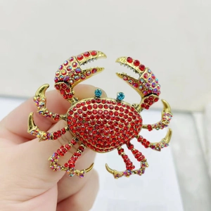 Golden crab brooch with vibrant red rhinestones and blue crystal eyes accessory