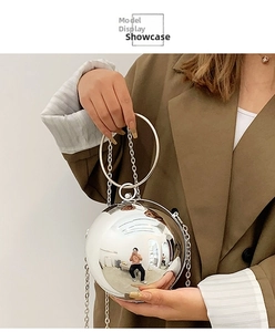 Dettaglio della borsa a sfera argento con manico ad anello metallico e tracolla a catena