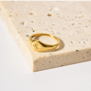 Close-up of gold plated stainless steel signet ring with engraved star on stone base