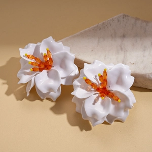 Detail of handmade white acrylic flower earrings with orange beaded stamens and silver pins